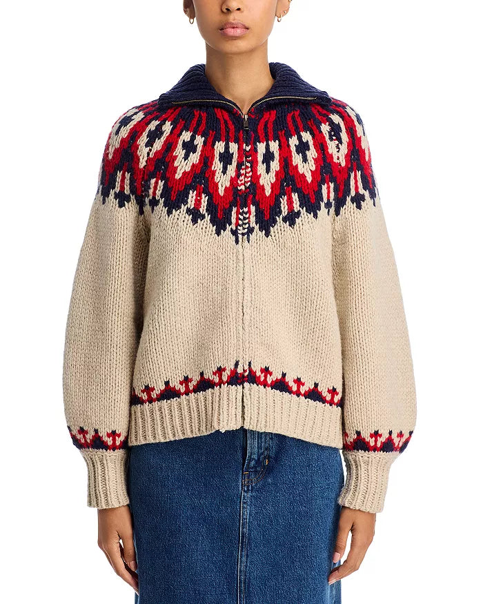 A person wears The Great Inc.'s The Nordic Sweater—100% cotton with red and navy Fair Isle patterns, a navy wide collared neck, and front zipper—paired with a blue denim skirt.