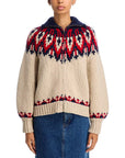 A person wears The Great Inc.'s The Nordic Sweater—100% cotton with red and navy Fair Isle patterns, a navy wide collared neck, and front zipper—paired with a blue denim skirt.