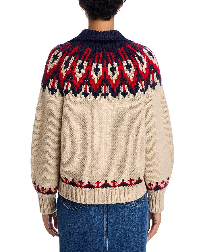 A person seen from the back wears The Great Inc.’s “The Nordic Sweater” in beige, featuring a collared neck and red, navy, and cream Fair Isle pattern on the yoke and cuffs, paired with blue jeans.