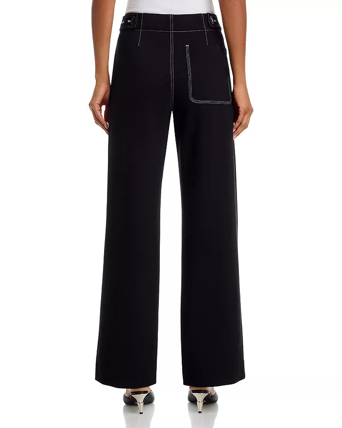 A person is seen from the back wearing Rag & Bone's Irina Pont Contrast Stitch Pants—a high-waisted, wide-leg style with relaxed fit, white contrast stitching, a large back pocket, zip fly closure—paired with black heels.