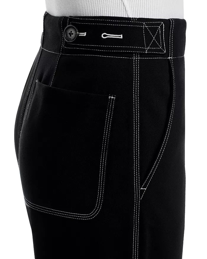 Close-up side view of a person wearing Rag & Bone Irina Pont Contrast Stitch Pants—black wide-leg style with white stitching, button closure, large front pocket, and visible waistband—paired with a tucked-in white top.