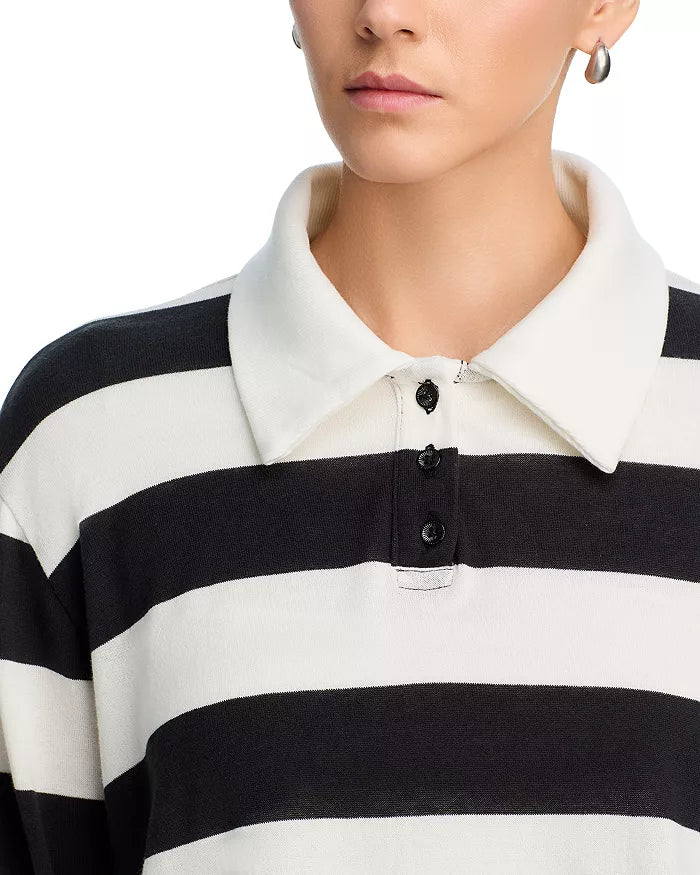 A person with short hair and hoop earrings is shown from the shoulders up, wearing the ASKK Long Sleeve Polo—a relaxed fit black and white horizontal striped shirt with a white spread collar and black buttons.