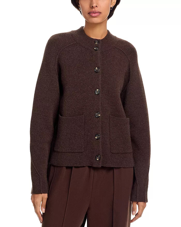 A person wears the Rag & Bone bridget mock neck cardigan in dark brown wool blend with long sleeves, two front pockets, and a round neckline, paired with matching brown trousers—a cozy layer for cold weather.