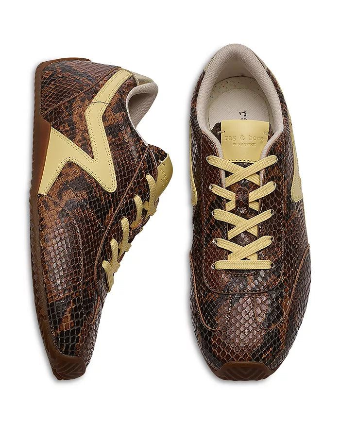 The Rag & Bone retro runner slim ultra sneakers feature a brown and black snake-print leather upper with beige accents on the laces, side panels, and tongue. One shoe is shown from above; the other displays the side profile.
