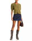 Cashmere Airy Cardi by FRAME styled with a denim mini skirt, tall brown boots, and dark brown handbag.
