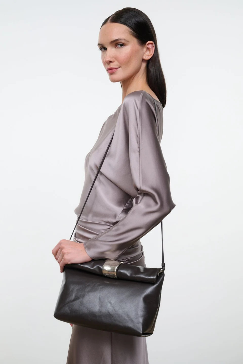 Staud Cuff Clutch in gray silk held by model in gray dress, plain white background, modern minimal style.