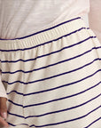 A close-up of a person wearing Ines De LA Fressange's Lucas Short in cream and navy stripes with an elastic waistband, paired with a light-colored top.