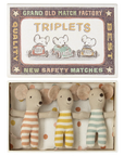 Three Maileg Mouse toys by Maileg, dressed in striped outfits, rest side by side in a small box labeled "Triplets," featuring charming mouse family illustrations and a vintage matchbox-style design.
