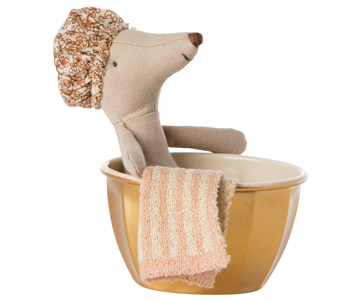 The Maileg Wellness Mouse / Big Sister by Maileg relaxes in a brown bowl "bathtub," wearing a floral shower cap while a pink striped washcloth hangs over the edge—creating a cozy, pampered scene perfect for imaginative play.
