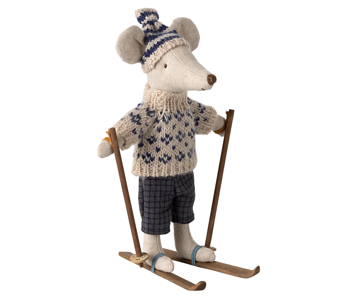 The Maileg Mouse by Maileg wears a knitted sweater, patterned hat, and checkered pants, standing on wooden skis with ski poles—a delightful addition to any mouse collection.