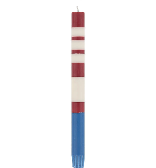 The Faire Striped Guardsman Red &amp; Royal Blue Candles S/2 feature hand-poured red and white stripes with a solid blue base, evoking the American flag. These Fair Trade candles stand upright with unlit wicks, shown against a white background.