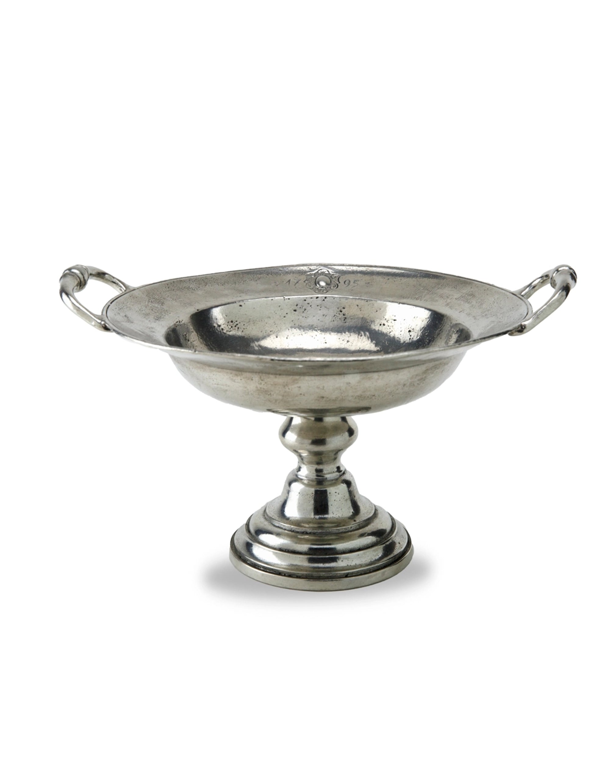 The Vintage 1795 Pedestal Bowl by Faire is a hand-made Italian pewter bowl with side handles, a wide reflective basin, and a round tiered base—offering timeless elegance.