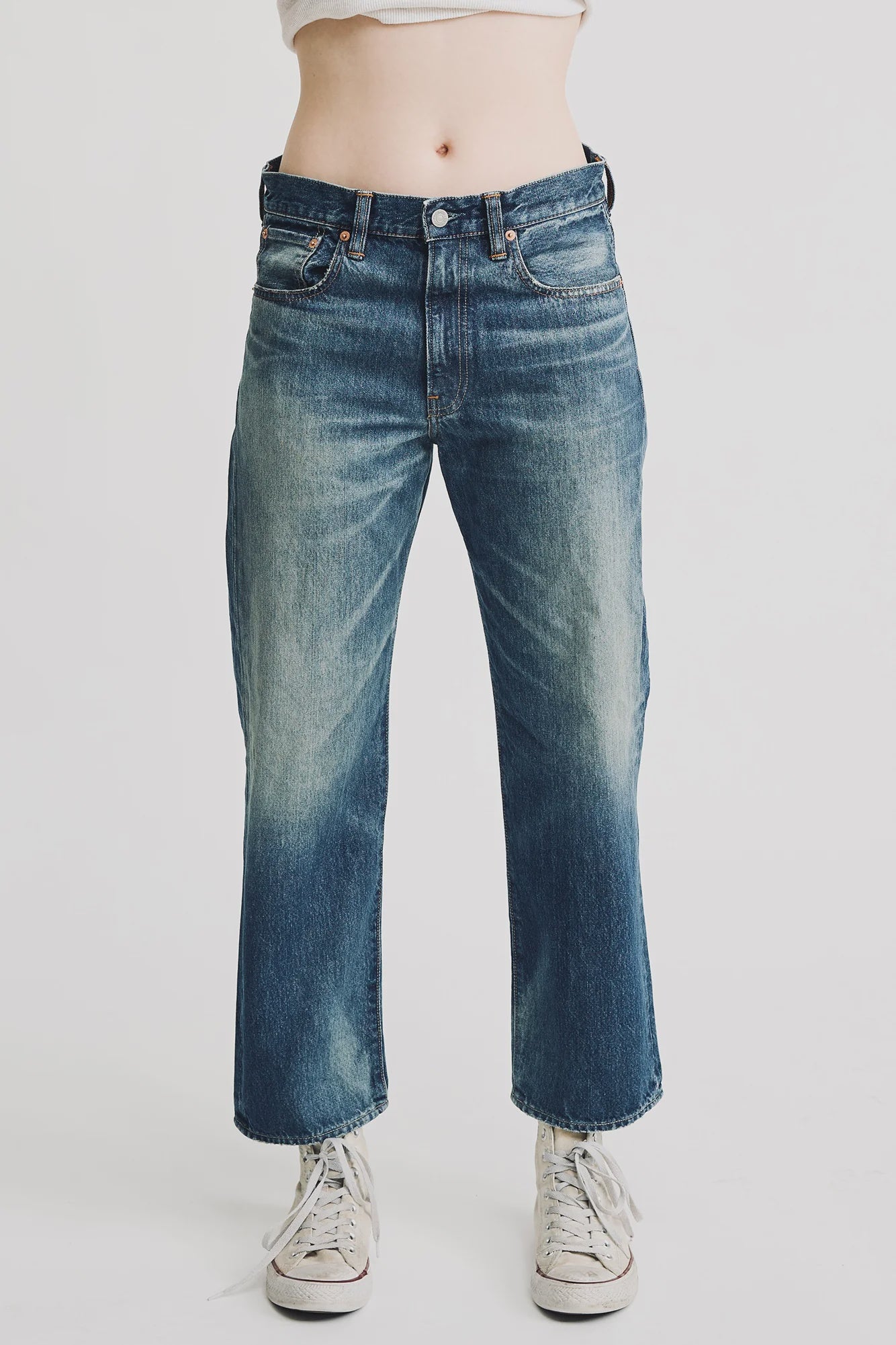 Model wears Denimist LUCY BF JEAN ESHER BLUE, a relaxed fit, high-waisted boyfriend jean with faded thigh details, paired with white sneakers against a plain white background.
