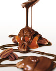 Velvety milk chocolate sauce cascades over pecans and caramel, crafting the decadent Faire LC Longhorns Milk Chocolate 6oz treat—Texas pecans and glossy caramel on a white backdrop.