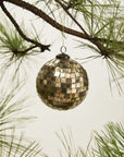 The Accent Decor Antiqued Disco Bal Orn 5" is a vintage-style ornament with a mosaic gold look, hanging from a pine tree branch with green needles against a neutral background.