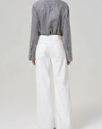 A person wearing a gray pinstripe button-up shirt with the Palma Straight Soft White pants by Citizens Of Humanity/AGOLDE. The recycled cotton blend and wide-leg silhouette contrast elegantly against the plain, light-colored background.