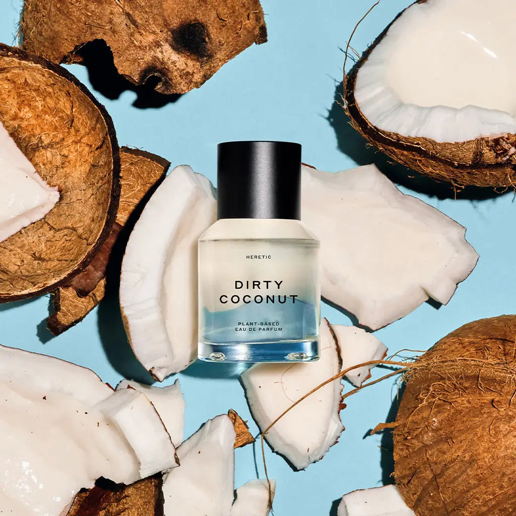 A bottle of Faire Heretic 50ML Perfume is displayed among cracked coconut pieces on a light blue background.