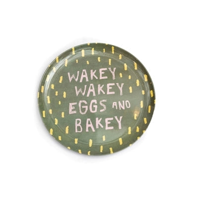 Serve your sunny side up Breakfast of Champions on Sugarboo Designs’ The Breakfast Club Plate Set—a round green plate with yellow dashes and “WAKEY WAKEY EGGS AND BAKEY” in pink and white.
