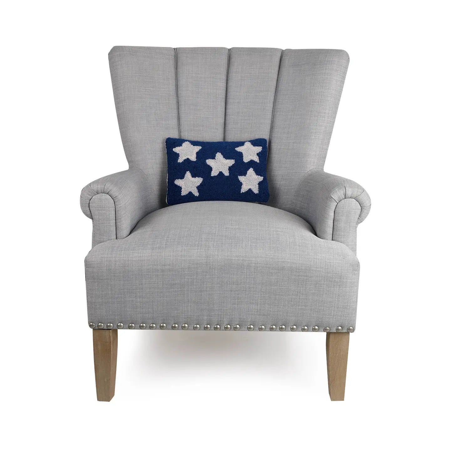 A light gray upholstered armchair with wooden legs and silver nailhead trim features Faire’s Patriotic Stars Pillow, a navy wool hooked throw pillow with five white stars—an ideal subtle 4th of July accent.