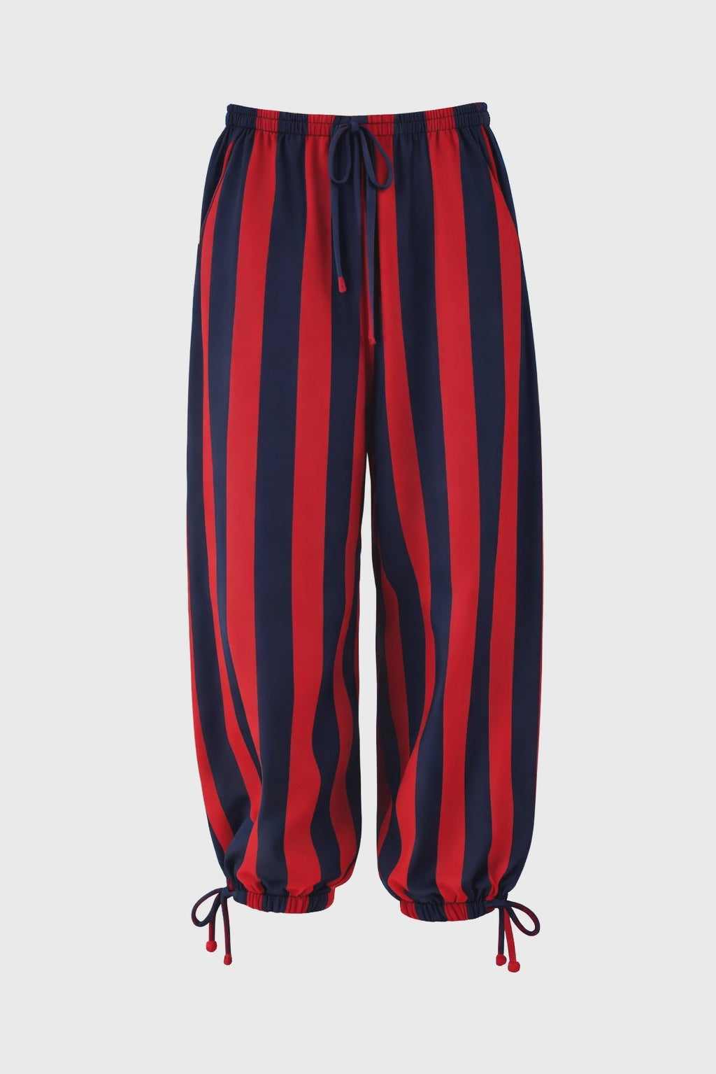 The Faire Surf Stripe Pant features vertical red and navy stripes, an elastic waistband with a handmade drawstring, and adjustable ankle ties, shown against a plain light background.