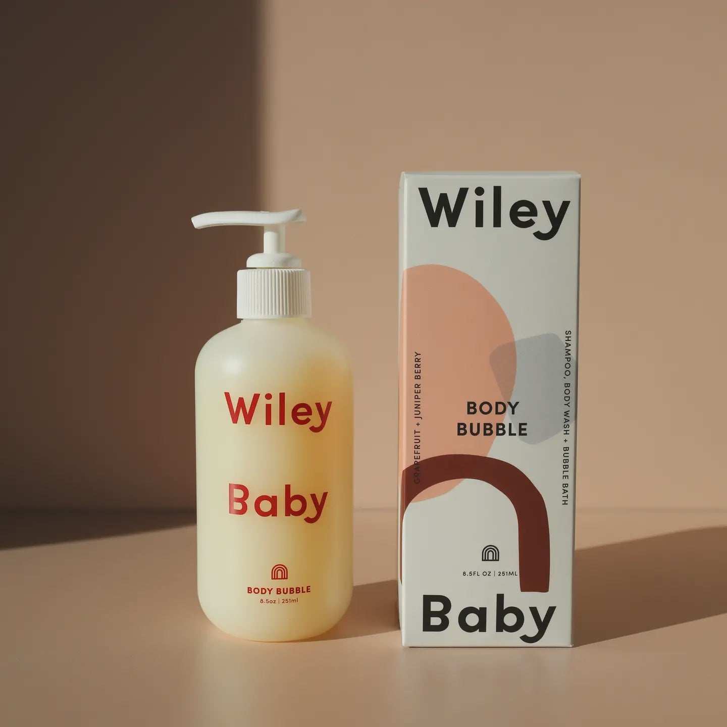 A beige bottle with a pump dispenser labeled "Faire" sits beside a matching box on a neutral background. This "Body Bubble Baby" product, ideal for baby skincare, features notes of grapefruit and juniper berry and contains 8.5 fl oz (250 ml) of nurturing goodness.