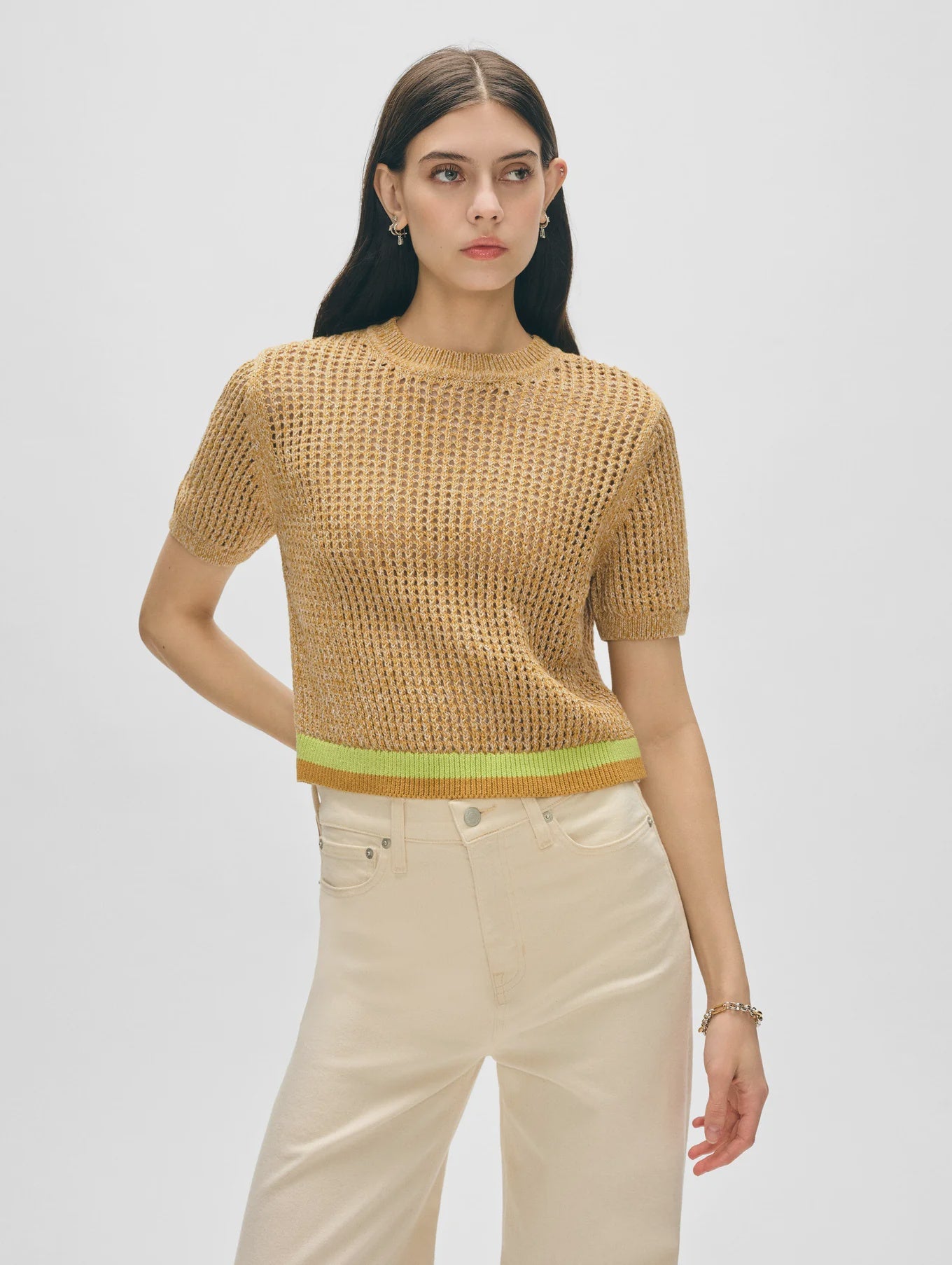 A woman with long dark hair wears a White + Warren Organic Cotton Mesh Tshirt and high-waisted off-white pants, standing against a plain light background.