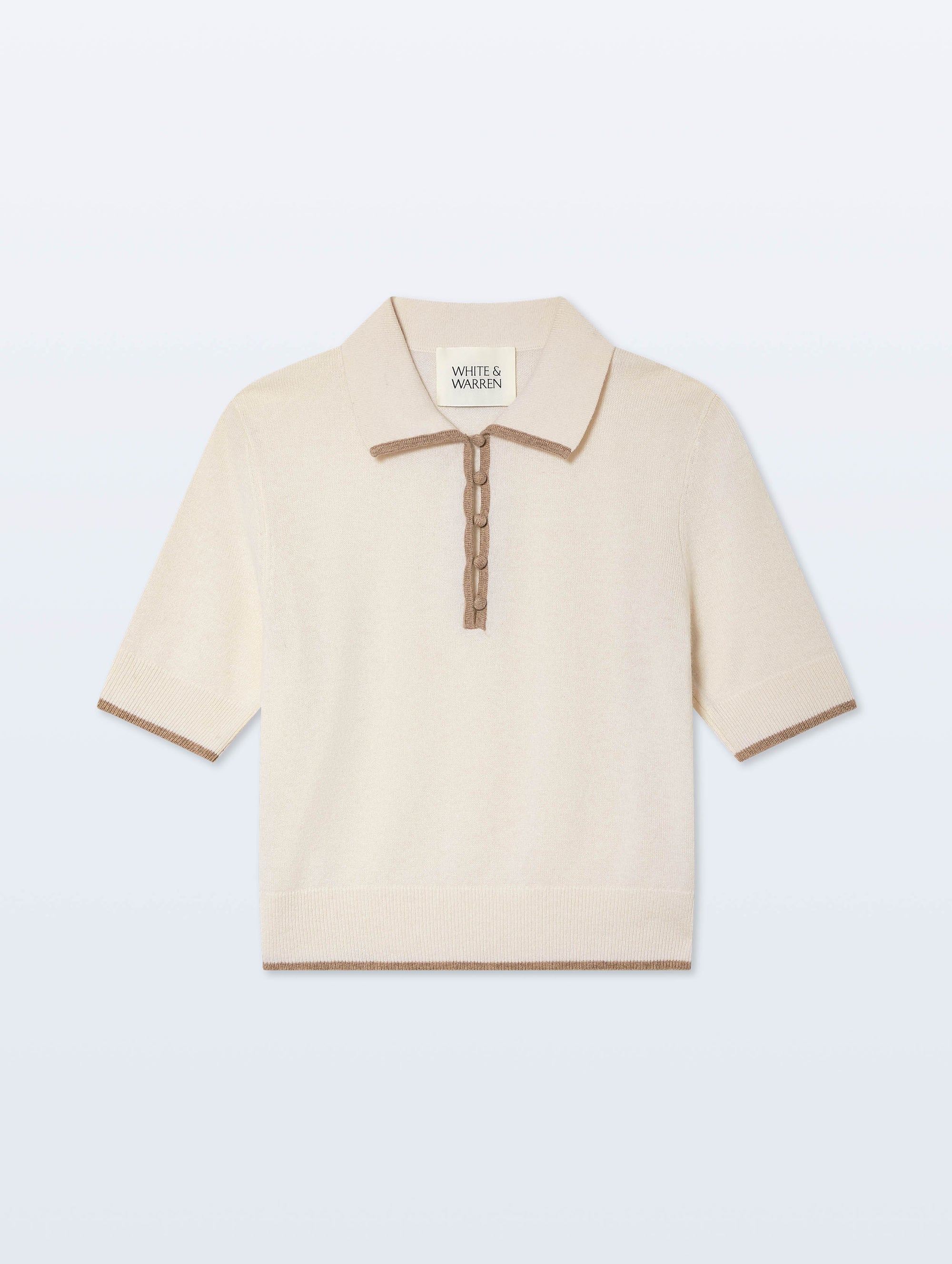 The White + Warren Cashmere Button Down Polo is a cream short-sleeve top with a ribbed collar, cuffs, and hem, accented by brown trim along the edges and button placket.
