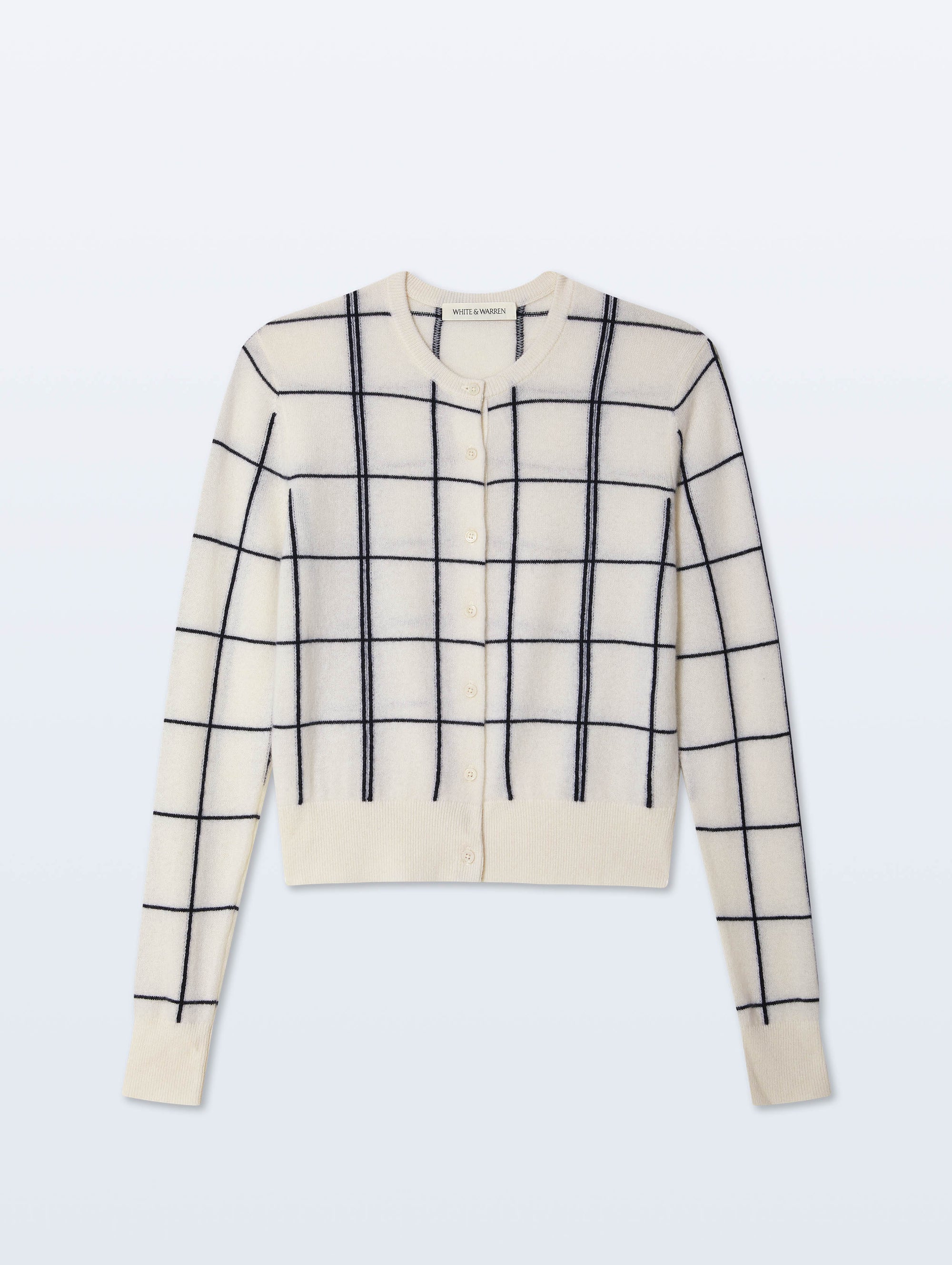 The White + Warren Cashmere Windowpane Cardigan features a cream color with black windowpane intarsia knit, straight fit, button front, and ribbed cuffs and hem, shown laid flat on a light background.