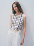 A person with wavy brown hair wears the White + Warren Cashmere Windowpane Vest with a navy blue pattern and loose white pants, posing against a plain light wall.