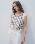 A person with wavy brown hair wears the White + Warren Cashmere Windowpane Vest with a navy blue pattern and loose white pants, posing against a plain light wall.
