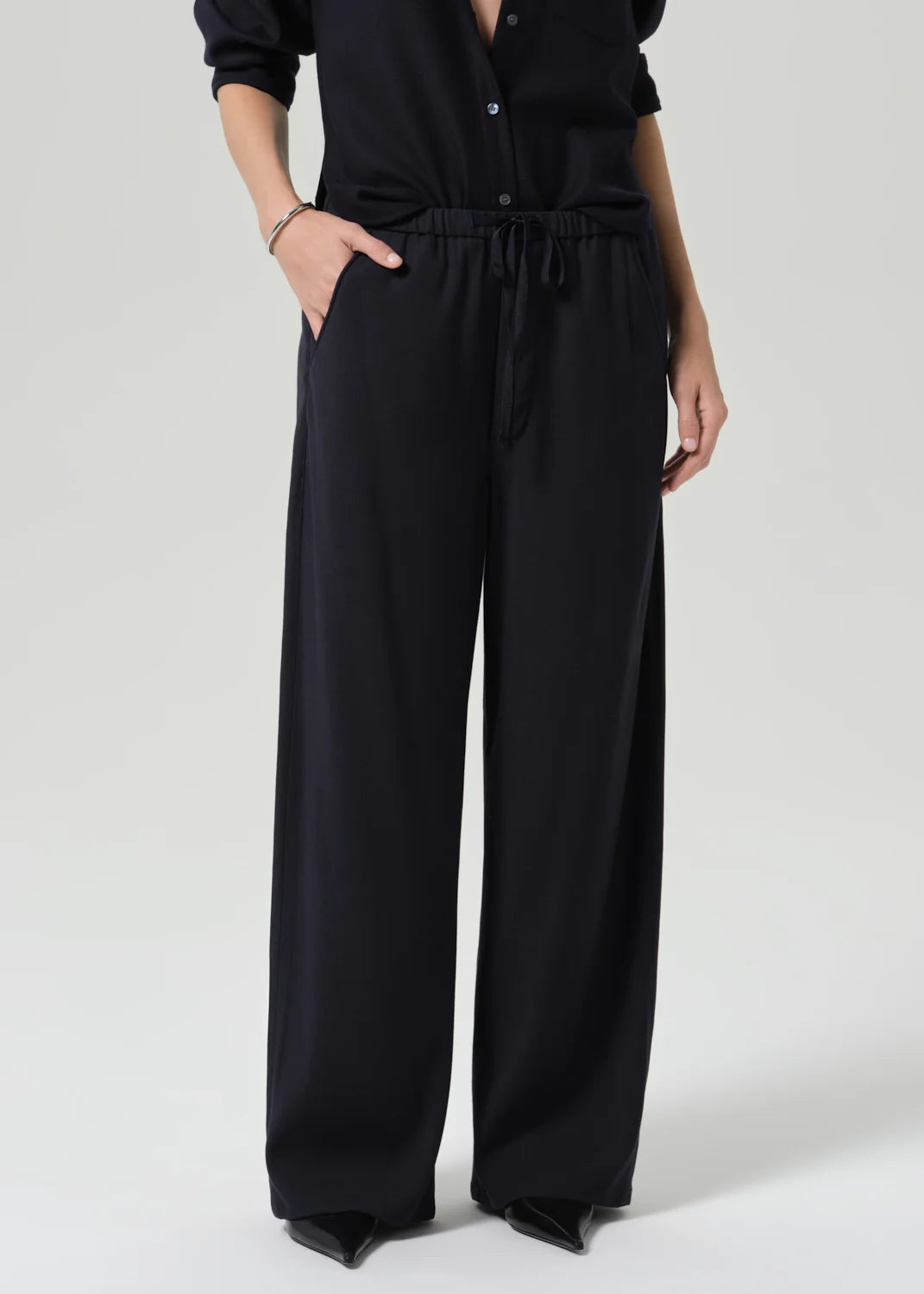 Aurora Pull On pants in Portofino Twill by Citizens of Humanity, styled with black pointed shoes and dark shirt.