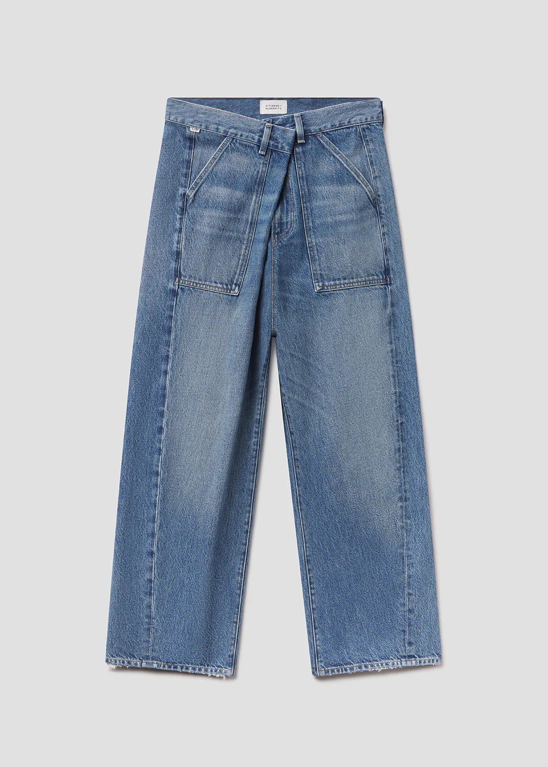 The Ines Utility Trouser by Citizens of Humanity/AGOLDE features wide-leg, high-rise medium indigo denim with front patch pockets, visible seams, and a straight cut, made from regenerative cotton denim and shown on a light gray background.