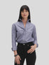 A woman with straight black hair models the Denim Country Club shirt by Sarah Alexandra, LLC. She pops the flared collar and pairs it with black jeans and a bracelet, standing against a plain light gray background.