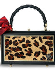 The Faire Leopard Supreme Bag is a rectangular leopard print cowhide purse with a black frame, gold accents, black bamboo handle, red bow, beige tassel, and four metal feet for added sophistication.