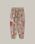The Gianna Cargo Pants by Me369 are loose-fitting with an elastic waist, an abstract red, beige, and black rodeo print, a white "girl" patch, and a red checkered patch on the side, shown against a plain background.