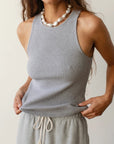 A woman in a gray Donni Rib Tank and matching drawstring pants, accessorized with a large pearl necklace, posing with one hand on her hip in Scottsdale, Arizona. Only her torso and lower face are visible.