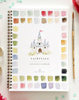 The Faire Watercolor Workbook is a spiral-bound beginner-friendly book with a castle cover and vibrant paint swatches, styled with a paintbrush, pink flowers, ribbon, and green beads on a white surface.