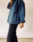 A person wearing The Barn Coat by Hey Gang and dark pants stands in front of a neutral background. The jacket, reminiscent of a chore coat with its large pockets, complements the casual and relaxed style as their right hand rests on their hip.