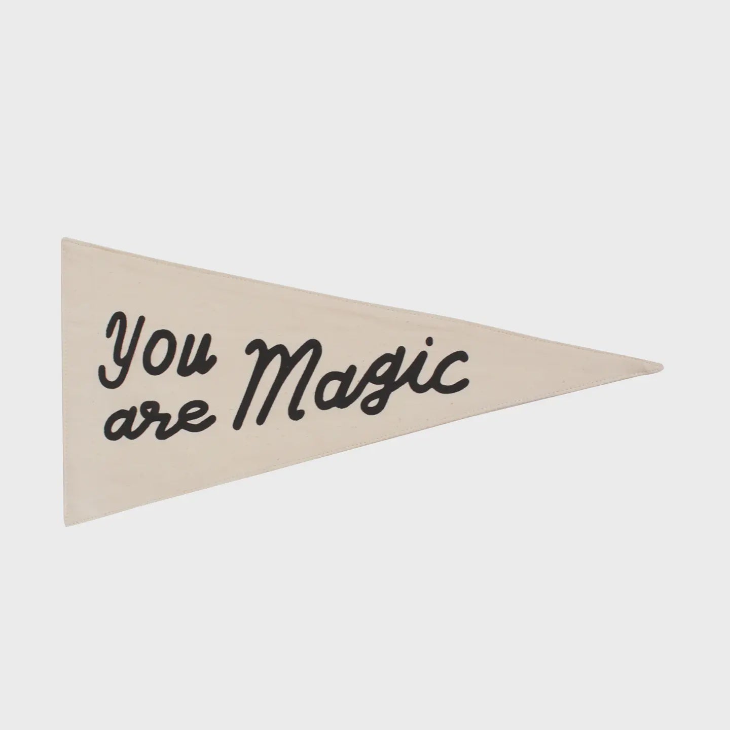 The Canvas Pennant by Faire is a beige triangular wall flag made from natural canvas, featuring the black handwritten text "You are Magic" screen printed for a charming touch.