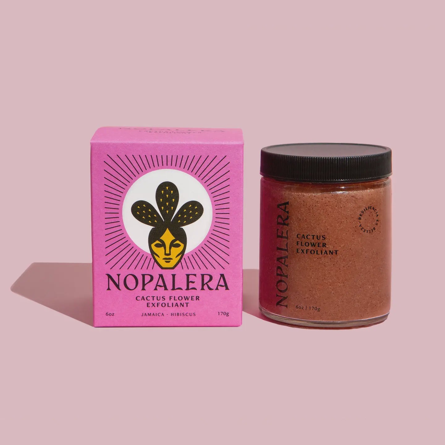 A pink box of Faire's Hibiscus Cactus Flower Exfoliant with an artistic logo stands next to an open glass jar of the product on a pale pink background, showcasing its luxurious prickly pear cactus blend.