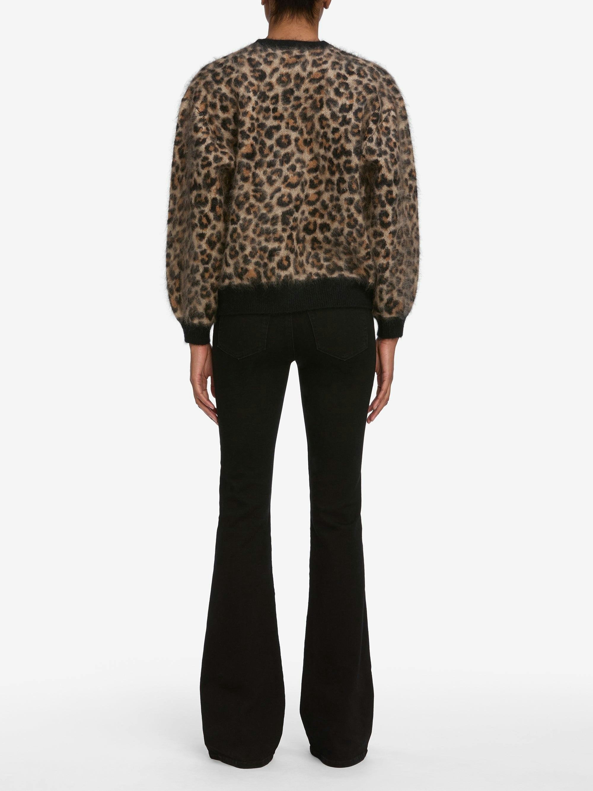 A person stands with their back to the camera, wearing the FRAME Brushed Leopard Cardi and black flared pants against a white background.