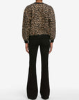A person stands with their back to the camera, wearing the FRAME Brushed Leopard Cardi and black flared pants against a white background.