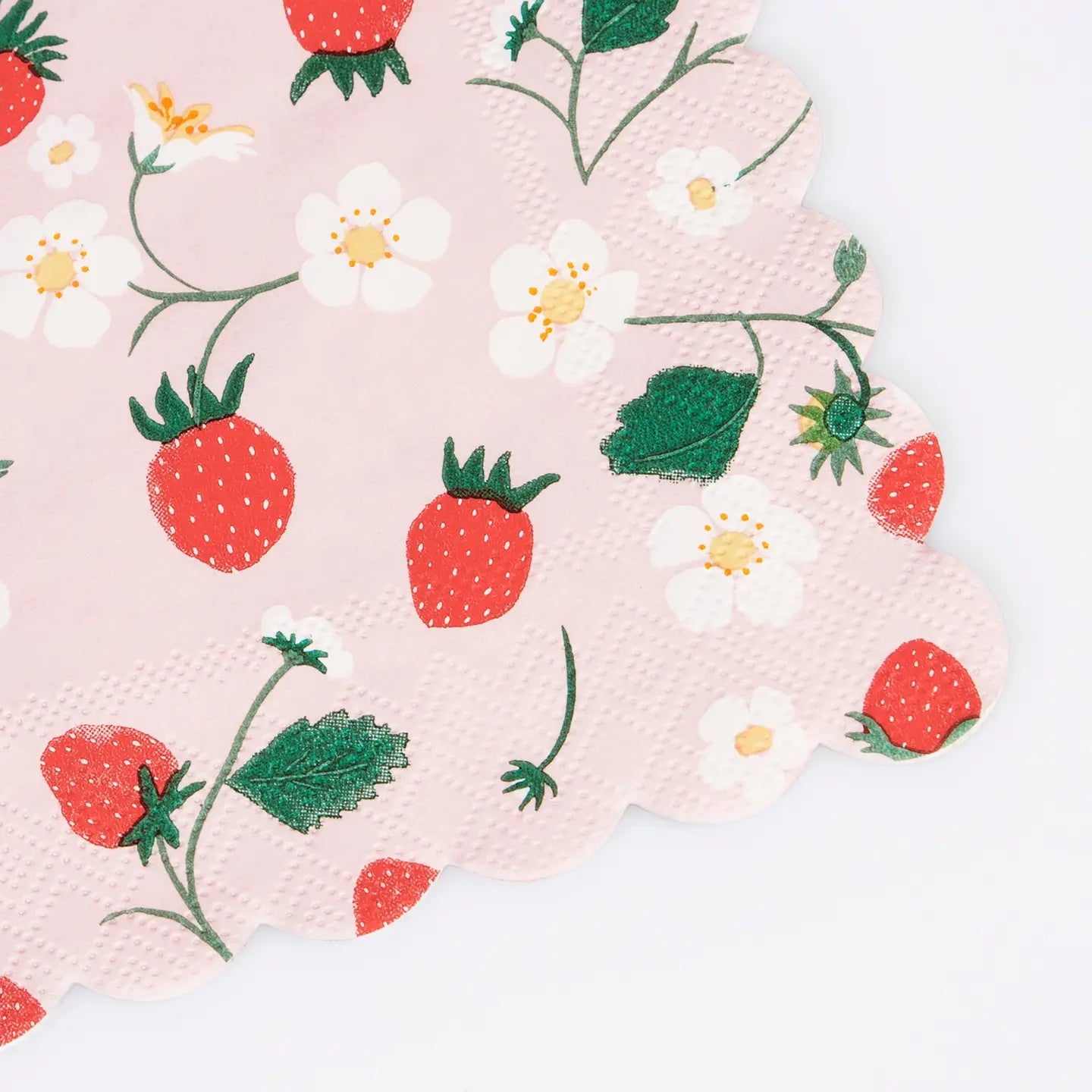 Faire Strawberry Napkins feature a scalloped edge and are adorned with red strawberries, green leaves, and white strawberry flowers, displayed on a pink background.