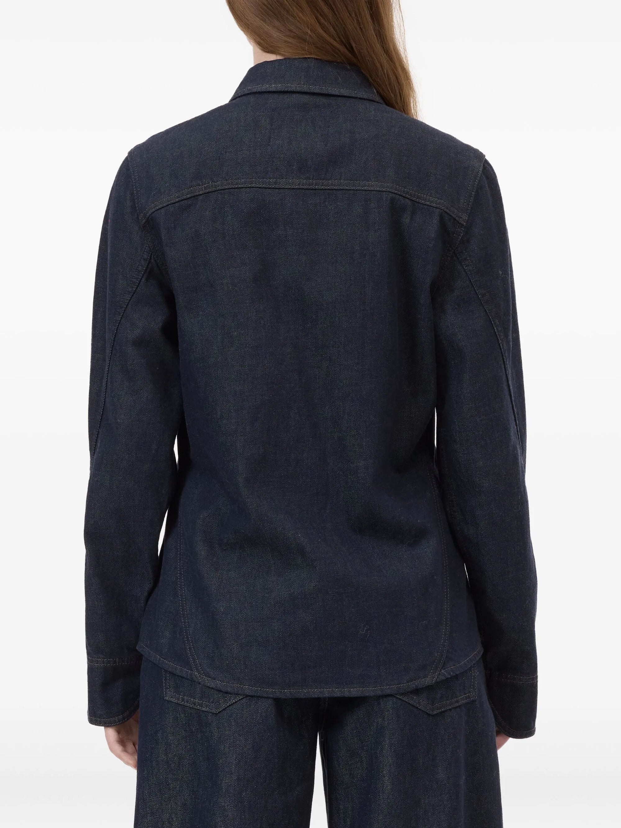 A person with long hair is seen from the back, wearing the CLOSED Seaming Shirt in dark blue denim with long sleeves and matching denim pants, standing against a plain white background.