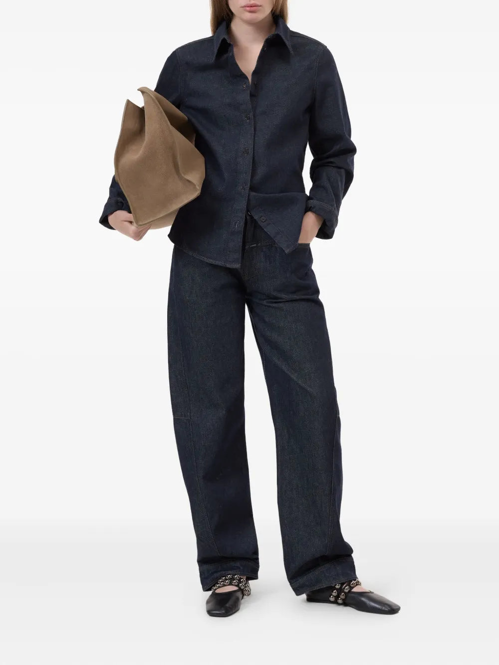 A person wearing the CLOSED Seaming Shirt, a dark blue cotton denim button-up with long sleeves, paired with matching wide-leg pants, holding a large brown bag and wearing black pointed-toe flats with decorative straps.