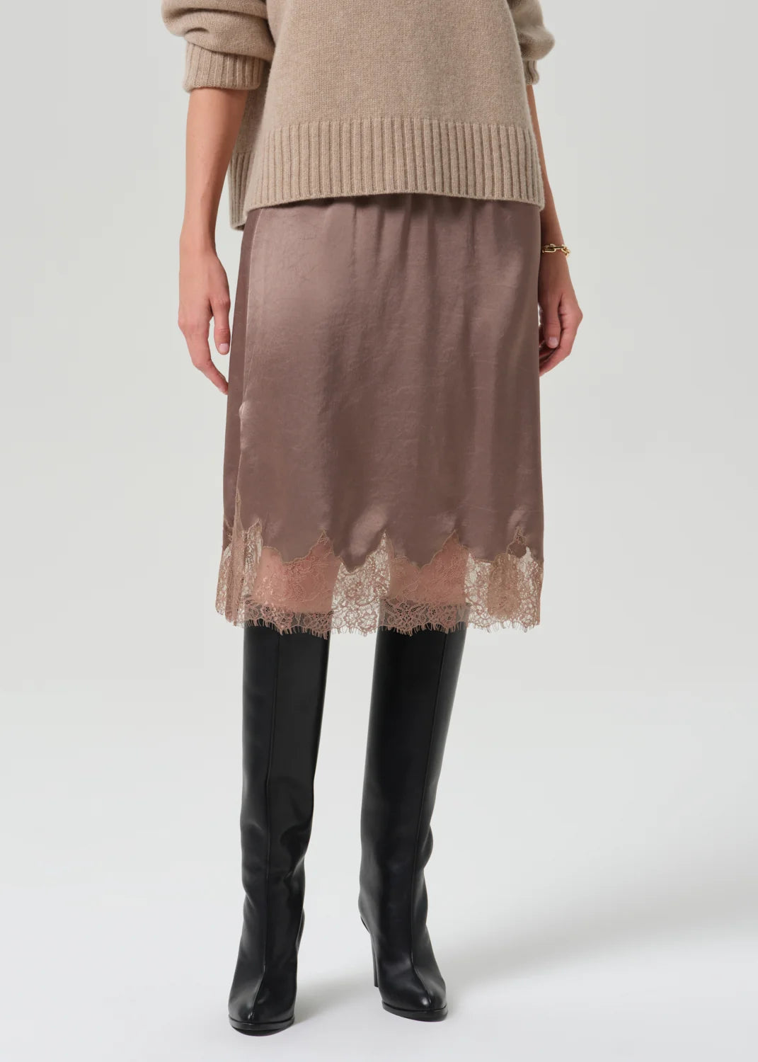 Lace-trimmed skirt from Citizens Of Humanity/AGOLDE paired with tan sweater and black knee-high boots.