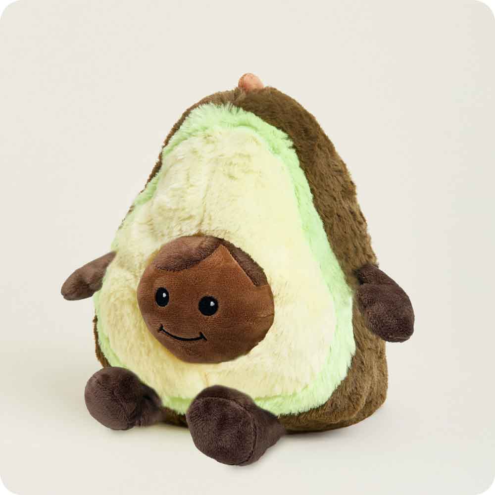 The Faire Avocado Warmies is a microwavable plush toy shaped like a smiling avocado with a brown seed belly, small arms and legs, offering extra comfort against a plain light background.