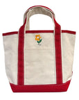 The Faire Deerest Darlin' canvas tote bag is cream-colored with red handles and trim, and has an embroidered yellow flower with green leaves on the front pocket.