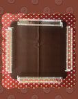 The Wild West Mahjong Mat ONLY by Faire is a square, dark brown mat with scalloped red edges and white circle patterns, topped with four transparent acrylic rods—one per side—and set against a matching patterned backdrop.