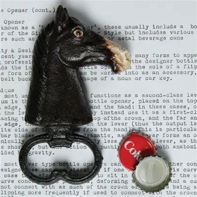 The HomArt Horse Head Bottle Opener, hand-painted, sits on a typed page with a removed bottle cap and a red "Cola" cap nearby.
